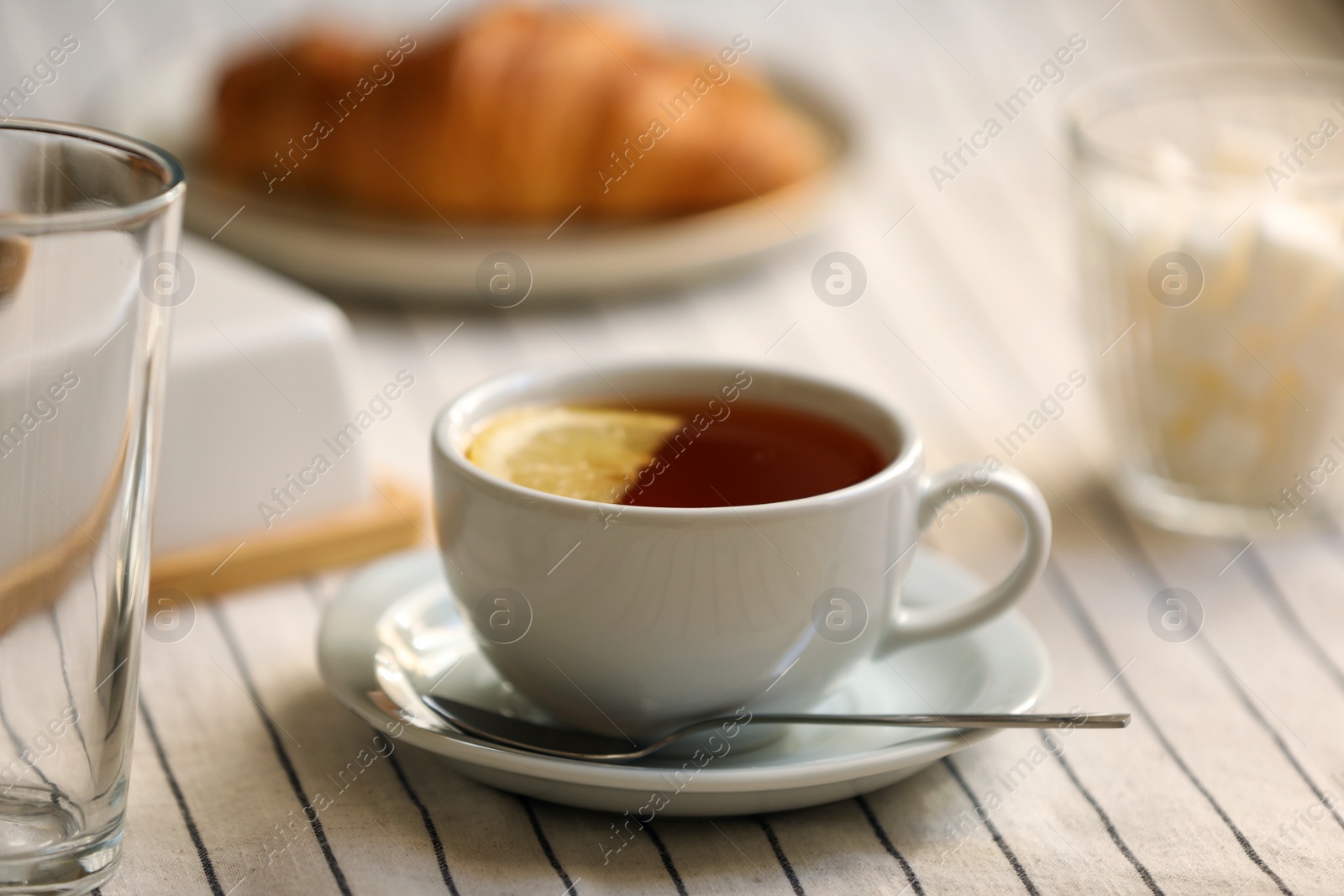 Photo of Cup of aromatic tea with lemon on table, closeup