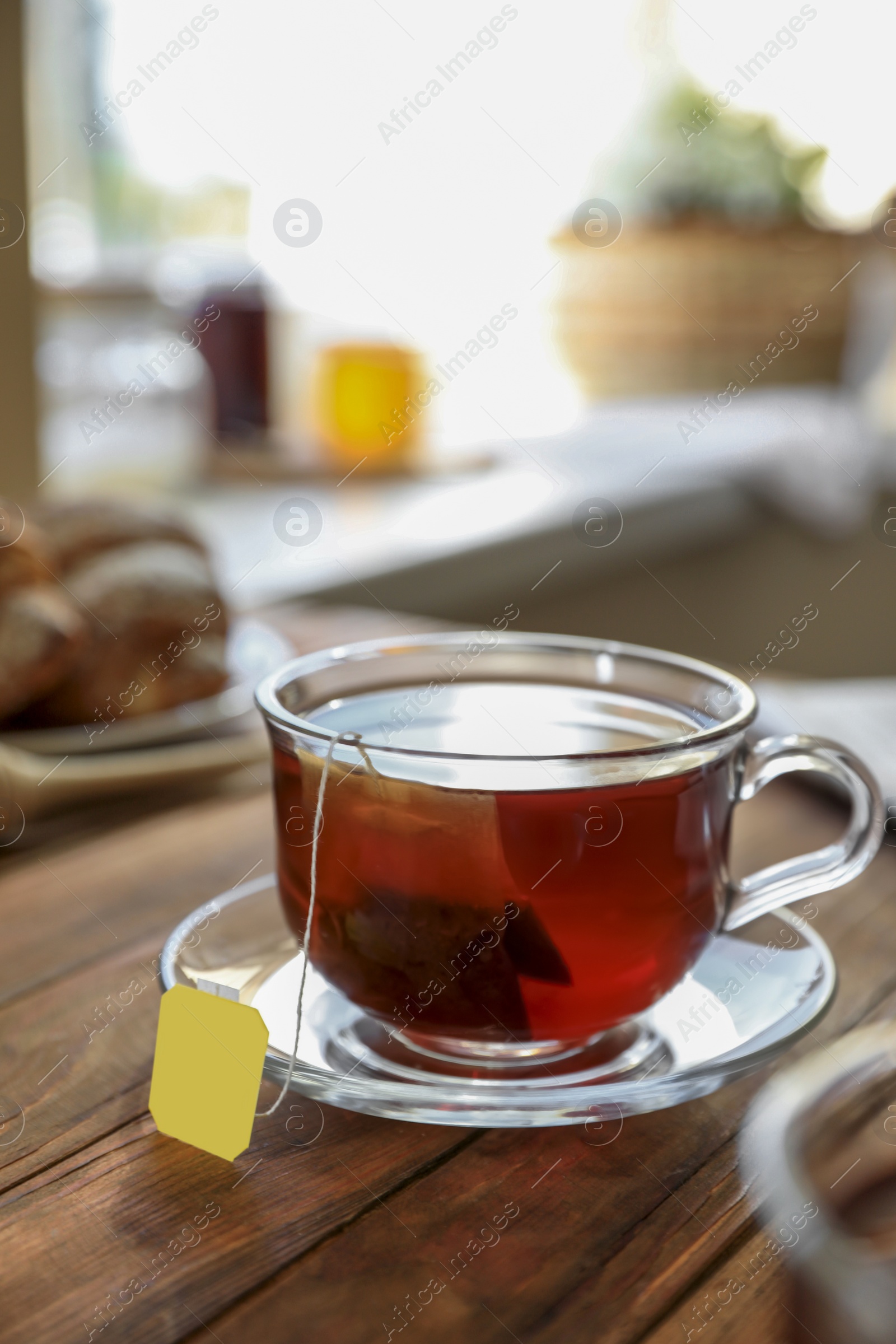 Photo of Tea bag in glass cup on wooden table indoors