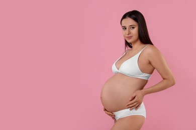 Photo of Beautiful pregnant woman in stylish comfortable underwear on pink background, space for text