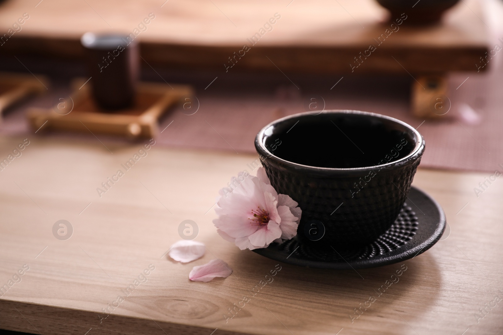 Photo of Cup with saucer for traditional tea ceremony and sakura flower on wooden table