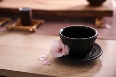 Cup with saucer for traditional tea ceremony and sakura flower on wooden table