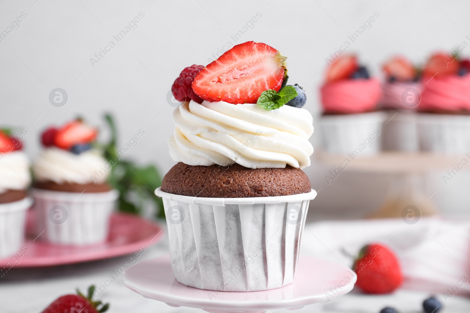 Photo of Delicious cupcake with cream and berries on stand, closeup