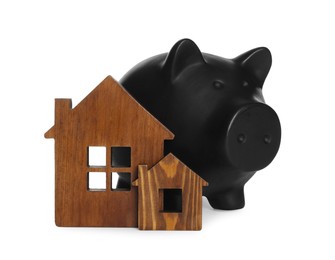 Piggy bank and wooden house models on white background. Saving money concept