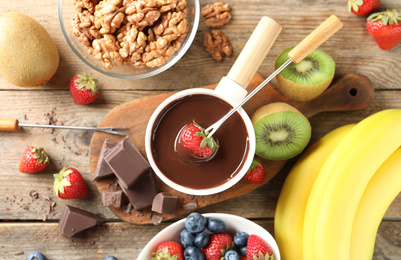 Photo of Flat lay composition with chocolate fondue in pot on wooden table