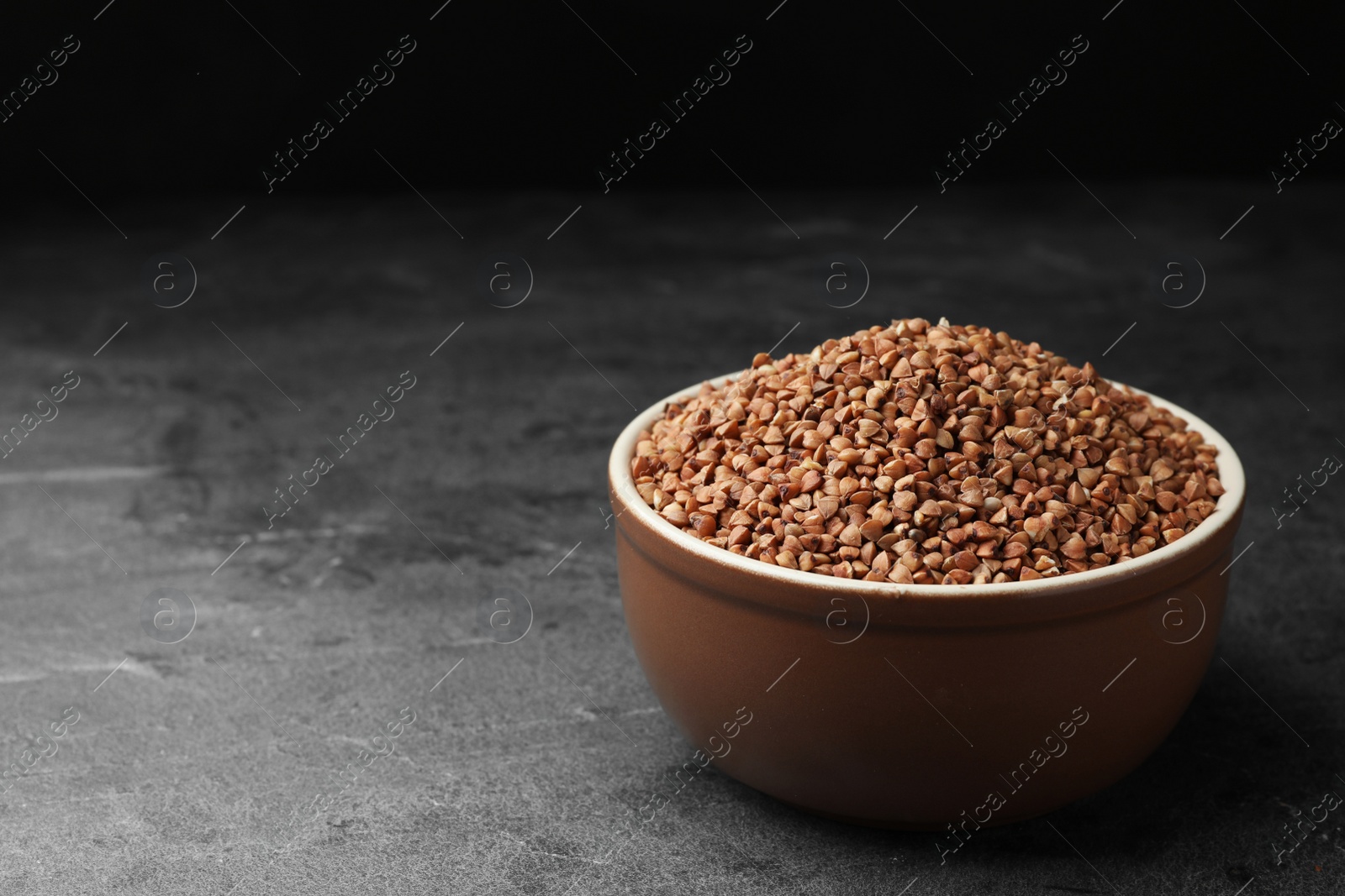 Photo of Buckwheat grains on grey table. Space for text