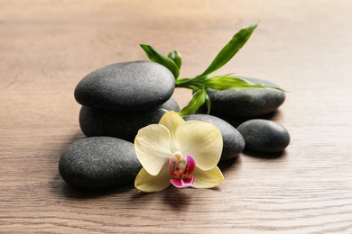 Spa stones, beautiful orchid flower and bamboo sprout on wooden table