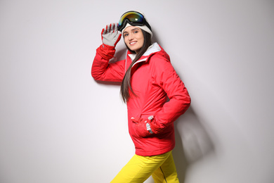 Woman wearing stylish winter sport clothes on light grey background