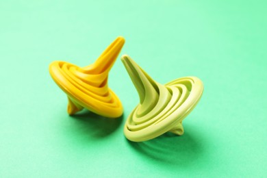 Two colorful spinning tops on green background, closeup