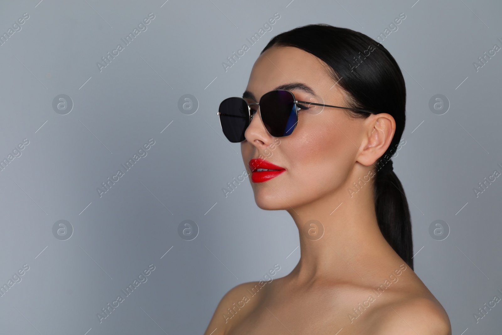 Photo of Attractive woman in fashionable sunglasses against grey background. Space for text