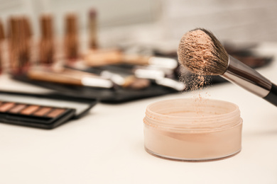 Photo of Professional brush of makeup artist and powder on dressing table