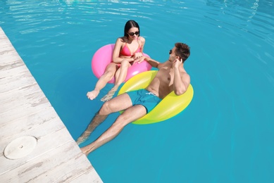 Photo of Woman in bikini with boyfriend swimming at resort. Happy young couple
