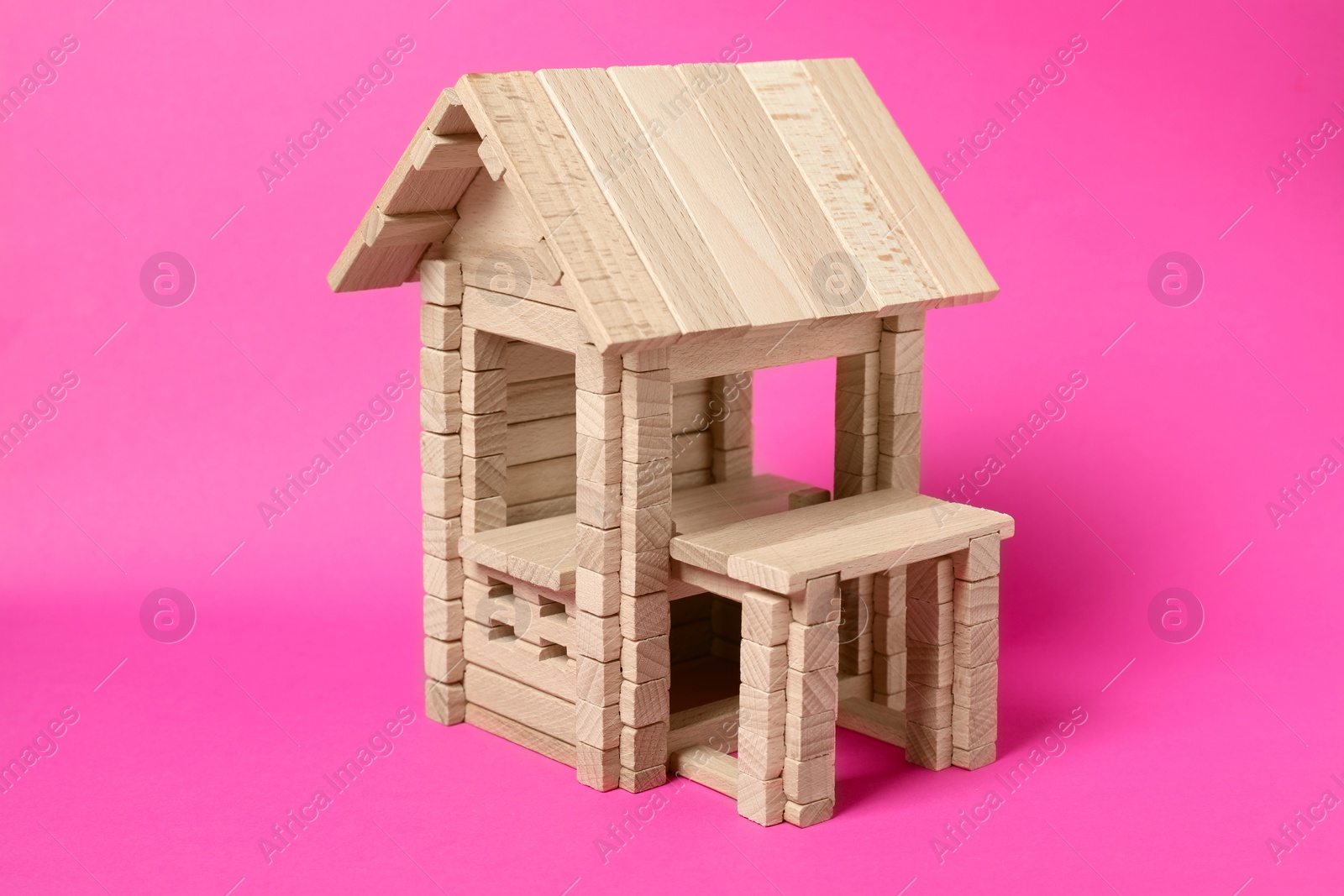 Photo of Wooden building on bright pink background. Children's toy