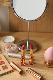 Makeup products and mirror on wooden dressing table