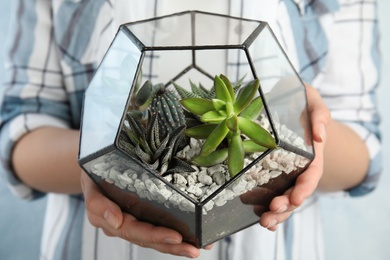 Photo of Young woman holding florarium with different succulents, closeup