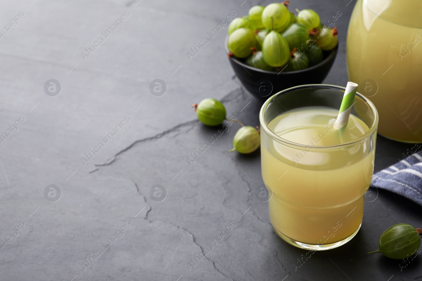 Photo of Tasty gooseberry juice on black table. Space for text