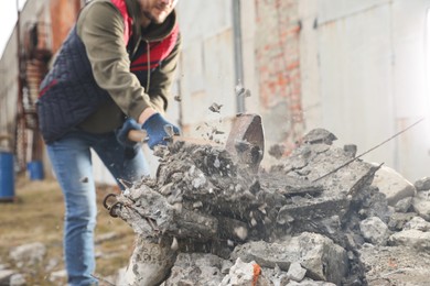 Photo of Man breaking stones with sledgehammer outdoors, closeup