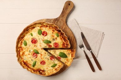 Photo of Delicious homemade cheese quiche and cutlery on white wooden table, flat lay