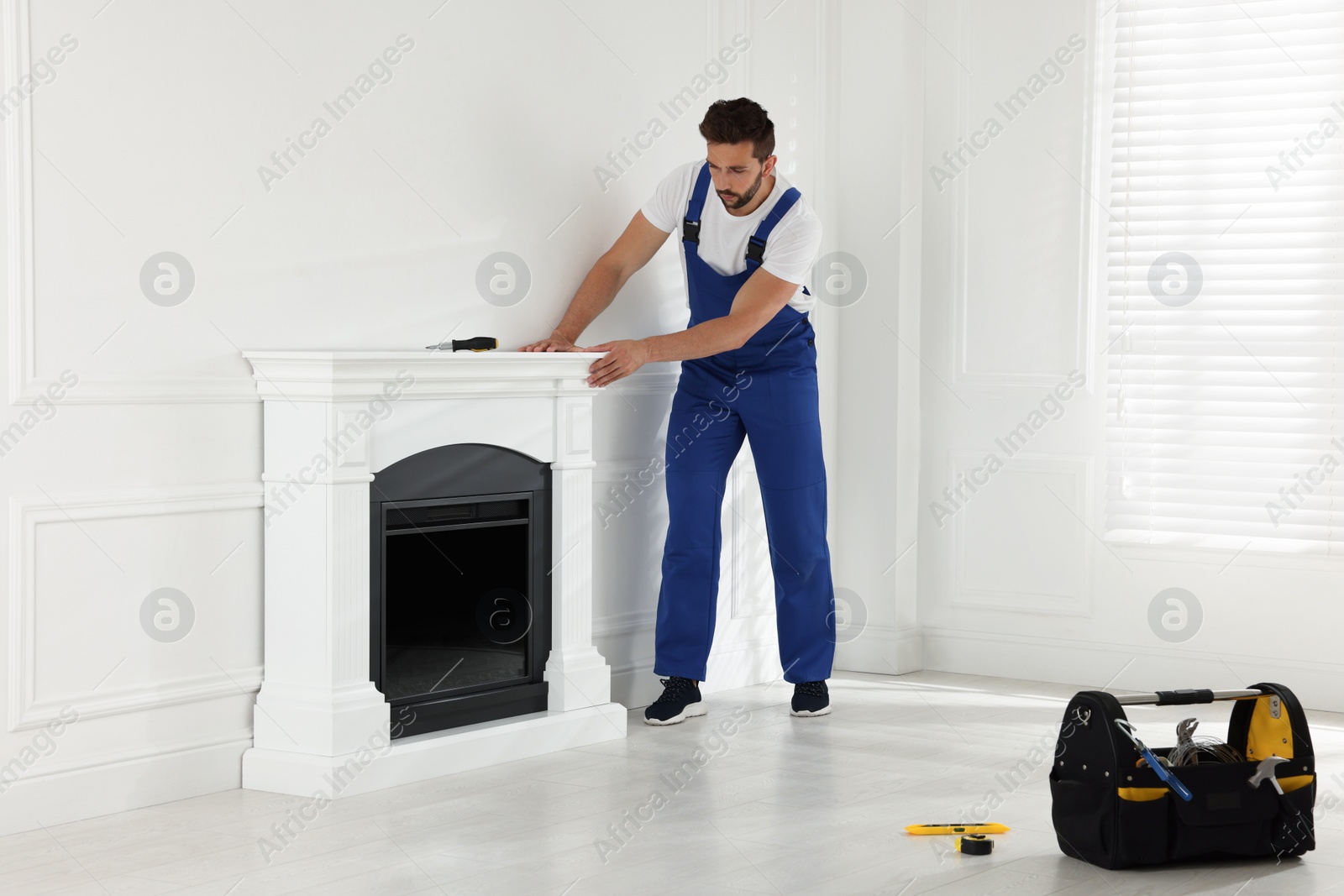 Photo of Professional technician installing electric fireplace in room