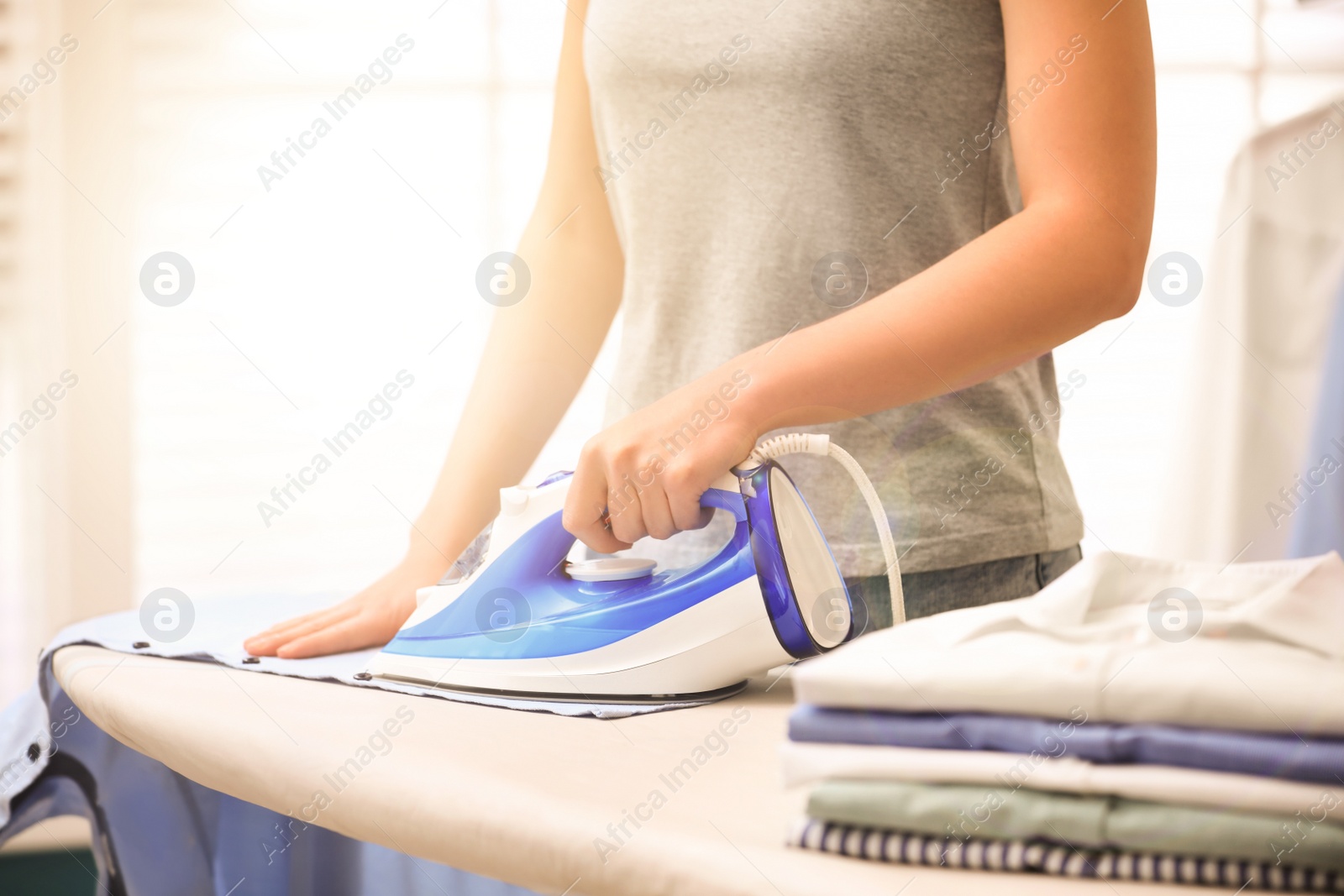 Image of Woman ironing clothes on board at home, closeup