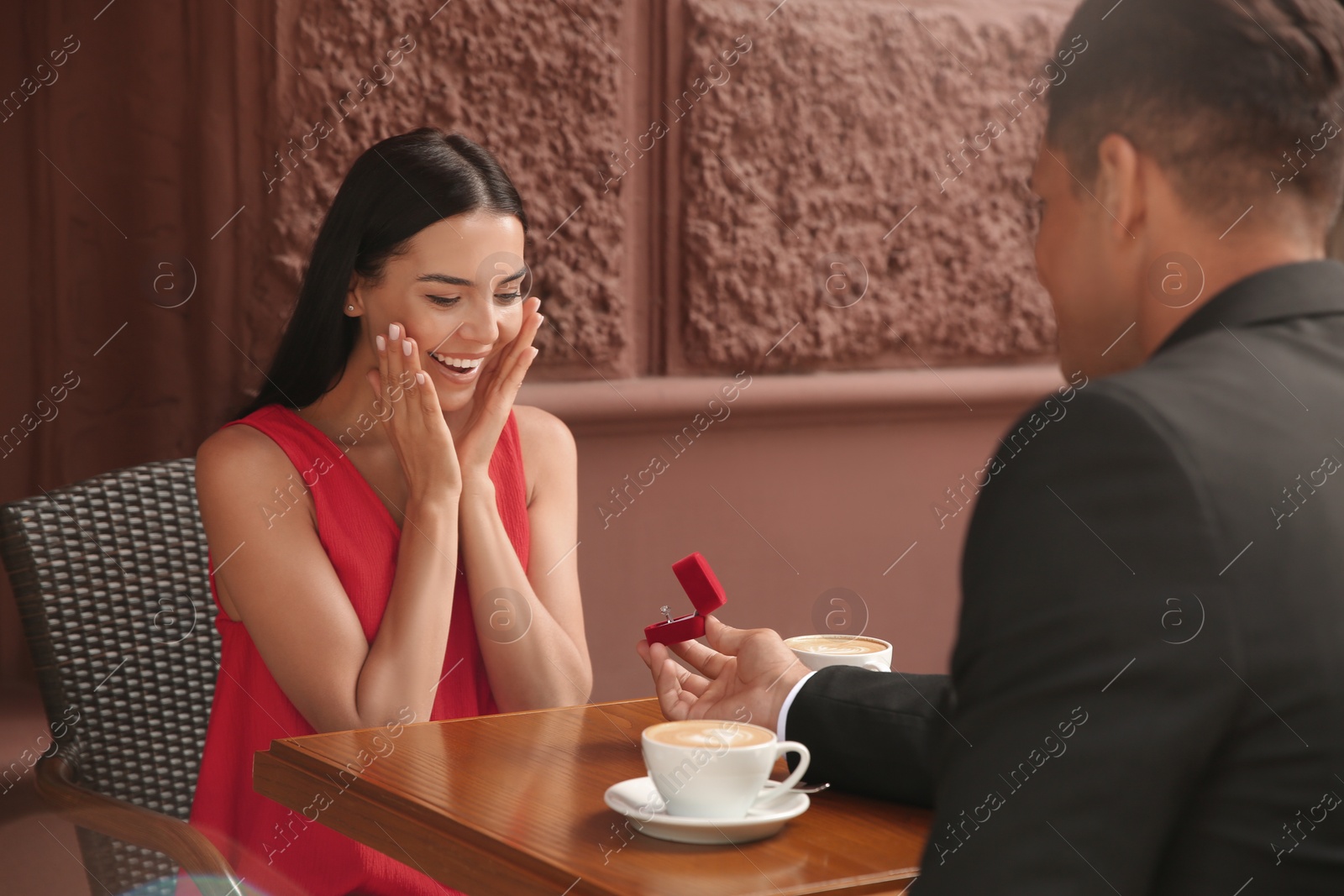 Photo of Man with engagement ring making proposal to his girlfriend in outdoor cafe