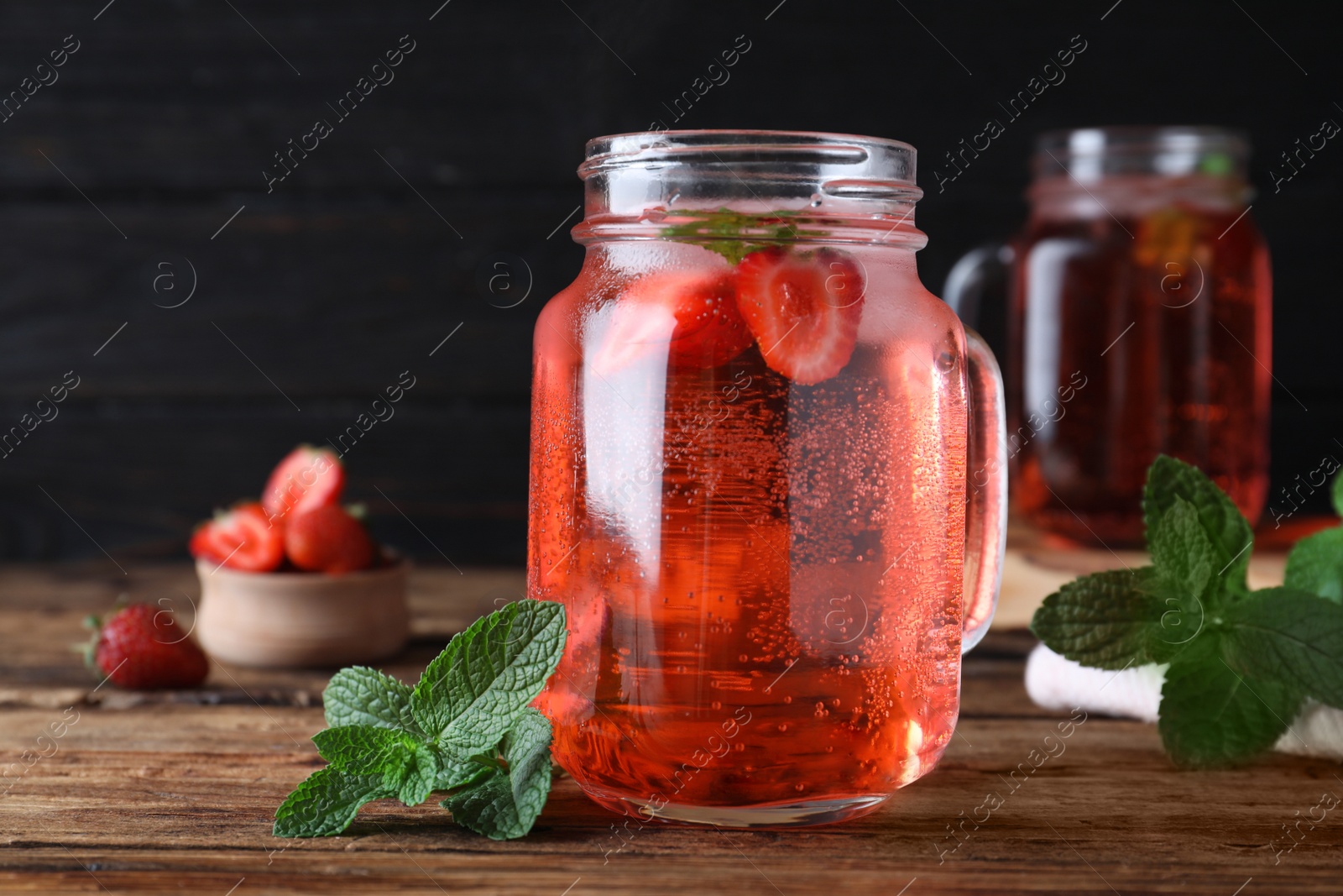 Photo of Delicious strawberry lemonade made with soda water and fresh mint on wooden table