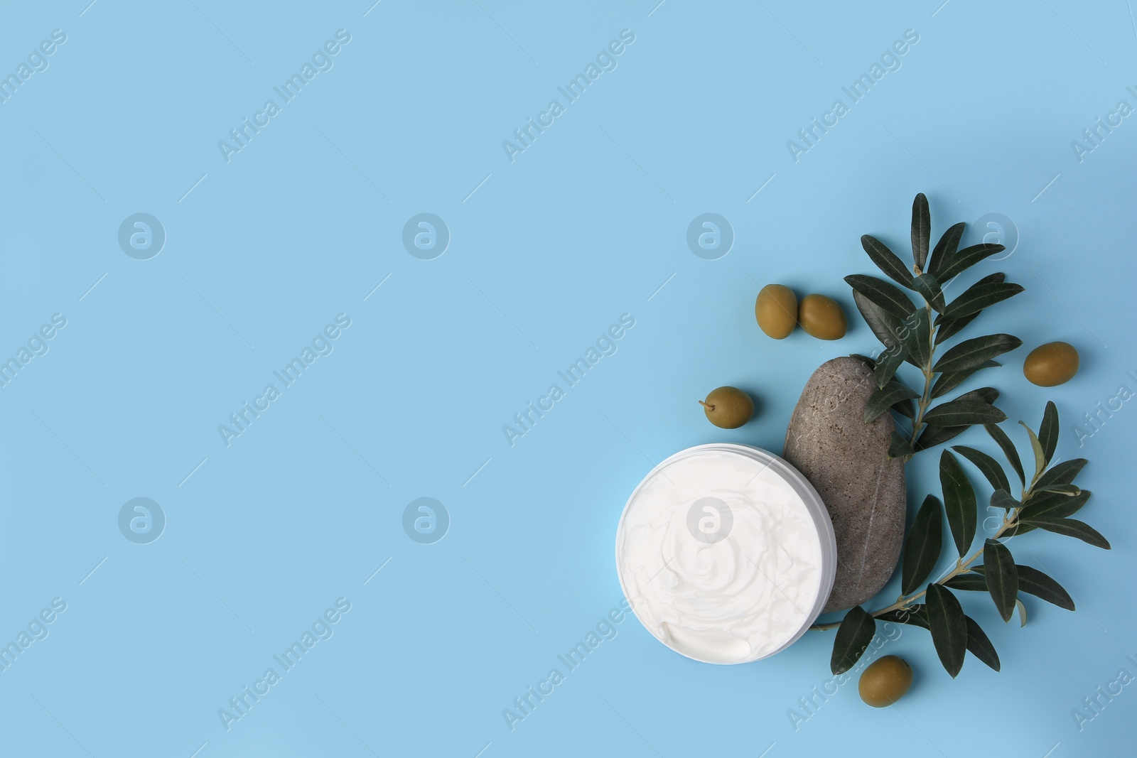 Photo of Flat lay composition with jar of cream and olives on light blue background. Space for text