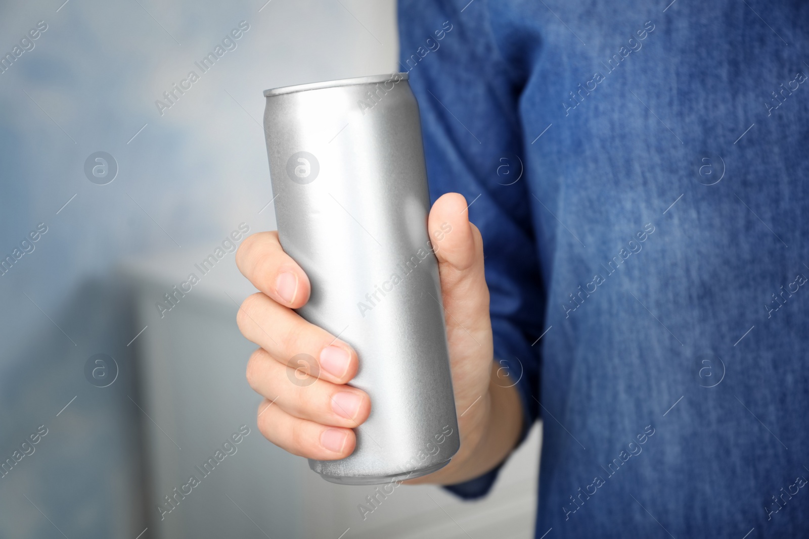 Photo of Woman holding aluminum can with beverage on blurred background, closeup. Space for design