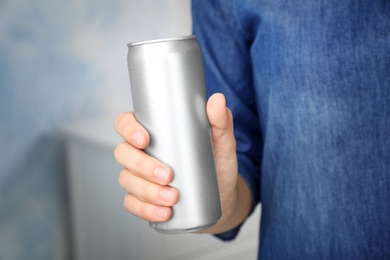 Woman holding aluminum can with beverage on blurred background, closeup. Space for design