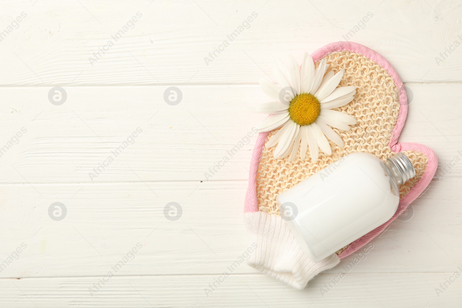 Photo of Exfoliating mitt, bottle of lotion and chamomile on white wooden table, flat lay. Space for text