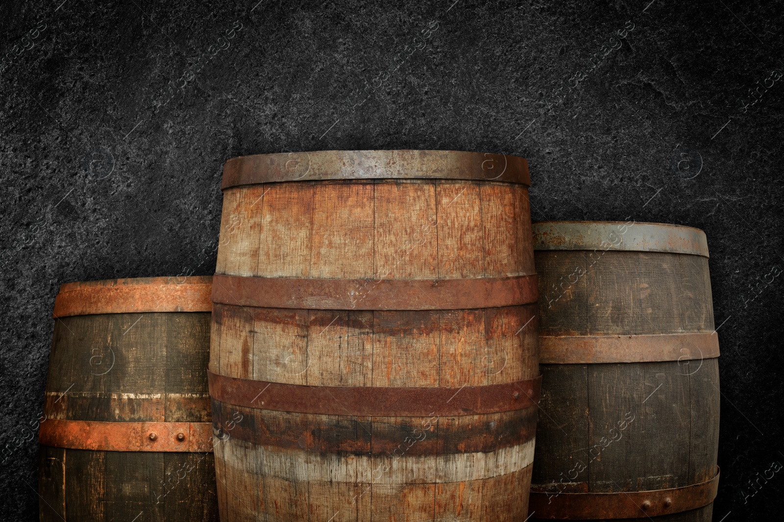 Image of Three wooden barrels near dark textured wall