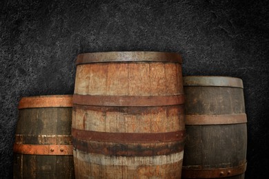 Image of Three wooden barrels near dark textured wall