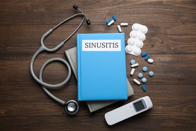 Photo of Notebook with word SINUSITIS, stethoscope, non-contact thermometer and different drugs on wooden background, flat lay