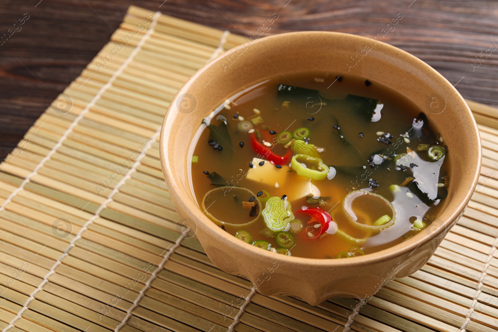 Photo of Bowl of delicious miso soup with tofu on wooden table. Space for text