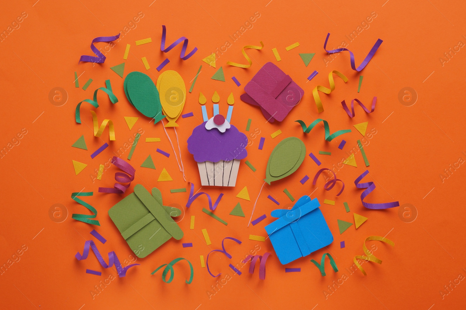 Photo of Birthday party. Paper cupcake, air balloons and gifts on orange background, flat lay