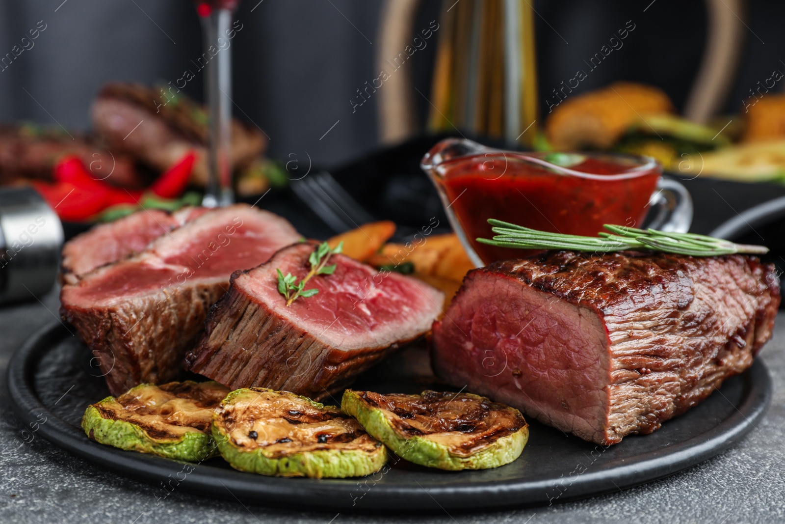 Photo of Delicious sliced beef tenderloin served on grey table, closeup