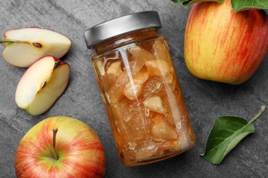 Tasty apple jam in glass jar and fresh fruits on grey table, flat lay