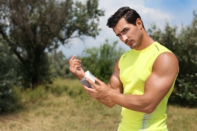 Photo of Young man checking pulse with medical device after training in park