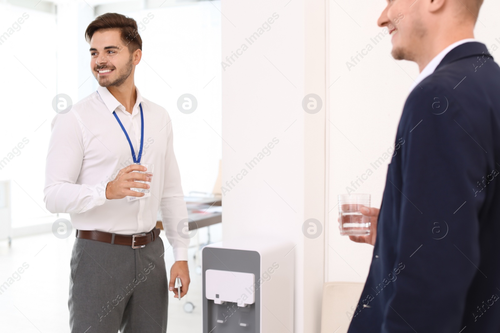 Photo of Men having break near water cooler at workplace