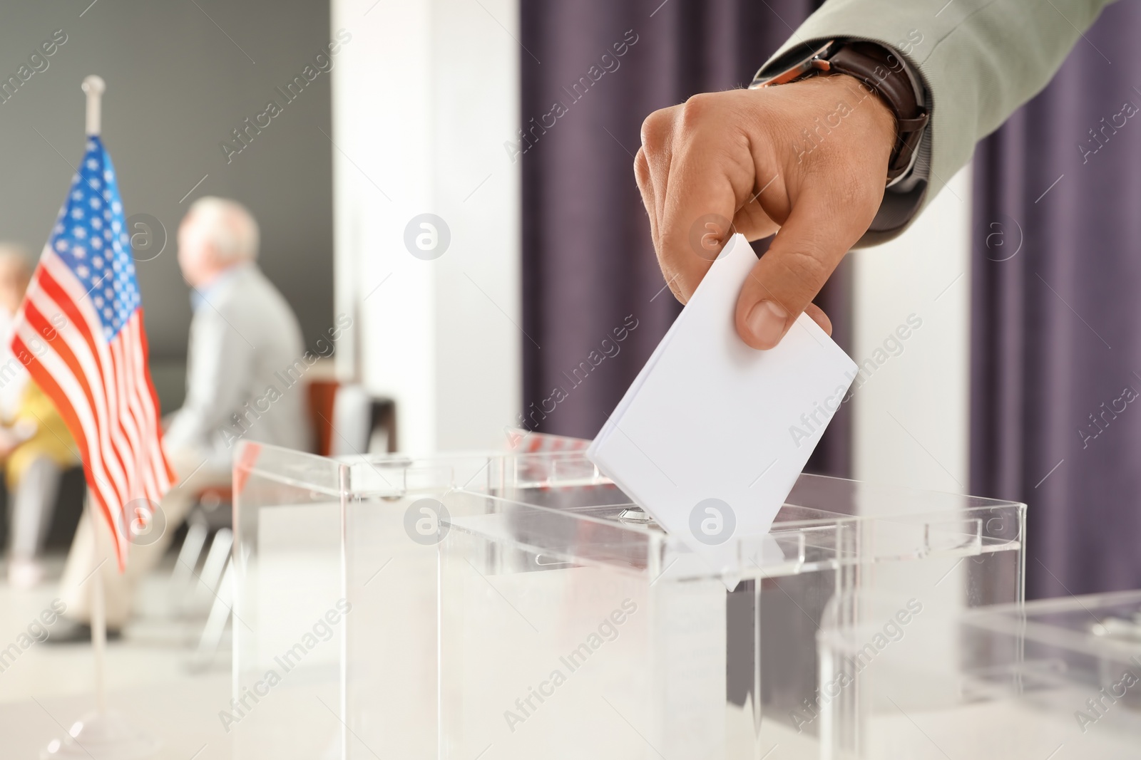 Photo of Man putting ballot paper into box at polling station, closeup