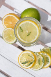 Photo of Delicious refreshing lemonade and pieces of citrus on white wooden table outdoors, flat lay