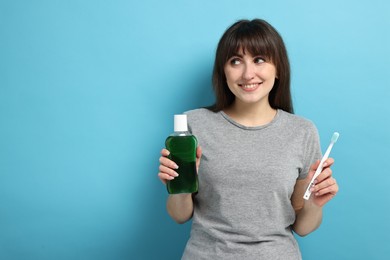 Photo of Young woman with mouthwash and toothbrush on light blue background, space for text