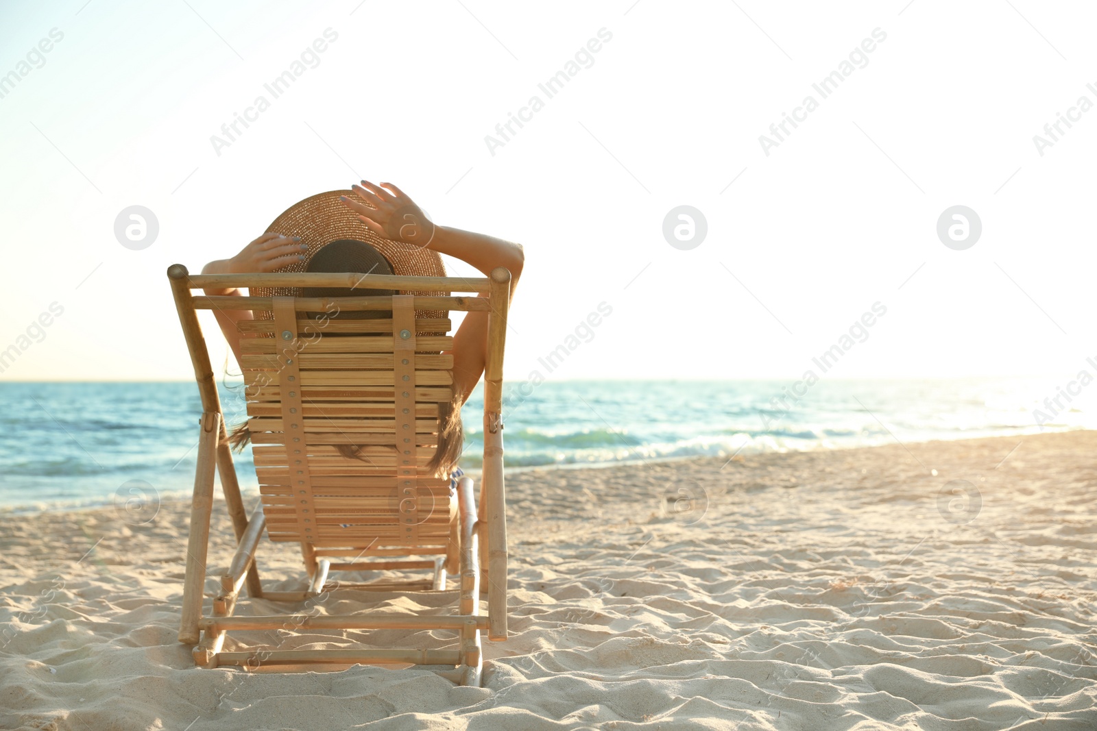 Photo of Young woman relaxing in deck chair on beach