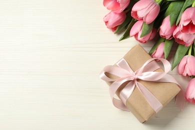 Happy Mother's Day. Beautiful pink tulips and gift box on white wooden table, flat lay. Space for text