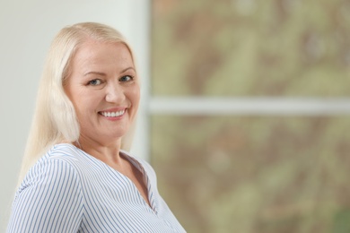 Portrait of beautiful older woman against blurred background with space for text