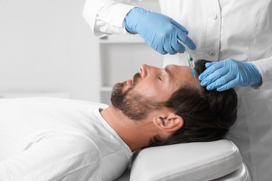 Trichologist giving injection to patient in clinic, closeup