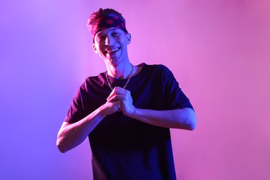 Photo of Stylish young man on color background in neon lights