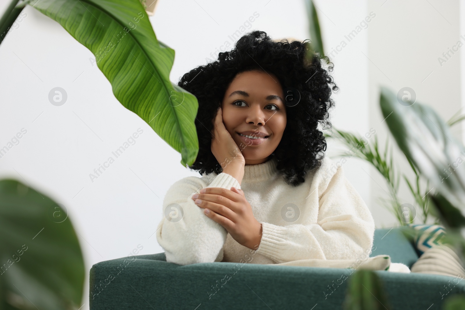 Photo of Relaxing atmosphere. Happy woman surrounded by beautiful houseplants indoors