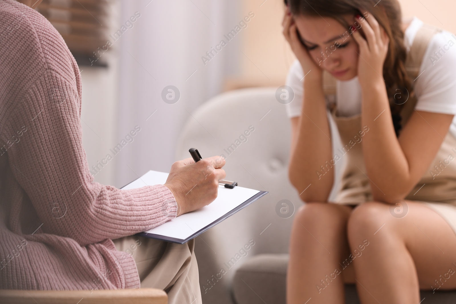 Photo of Psychotherapist working with teenage girl in office, closeup