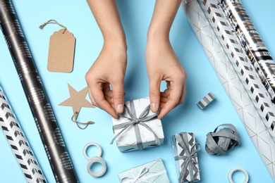 Woman decorating gift box on color background, top view