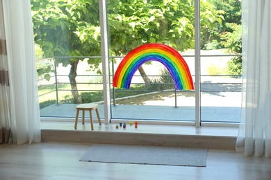 Painting of rainbow on window and paints indoors. Stay at home concept